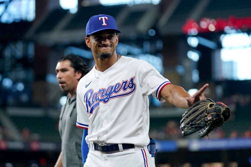 Texas Rangers' Bubba Thompson waves to fans as he walks to the dugout during the first...