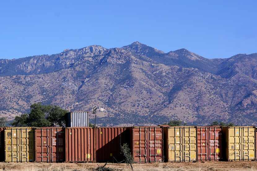 Una larga fila de contenedores espera para ser instalada a lo largo de la frontera donde...