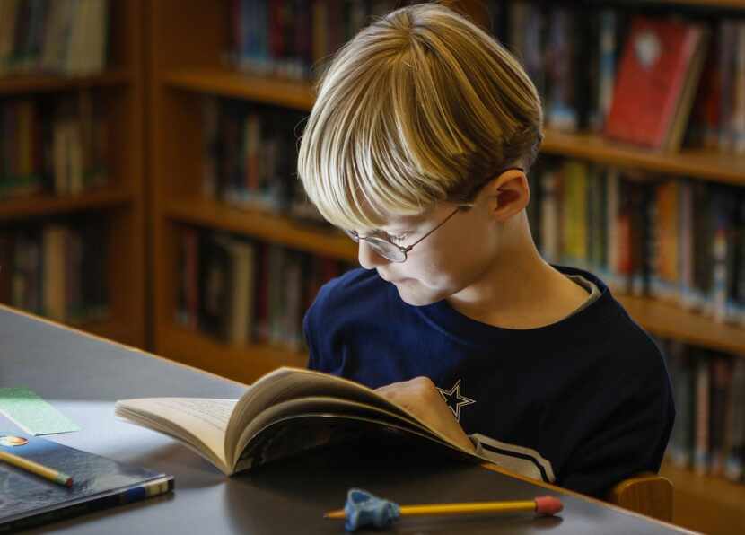 
Elementary student David McAtee, 7, reads a book in the library at the school.
