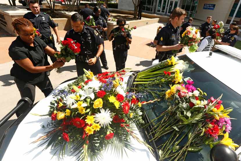 Policías de Dallas mueven flores que fueron dejadas en la estación a un carro en el Jack...