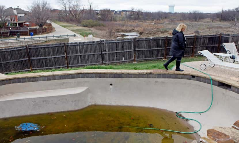 
Laura Brewer walks alongside her family’s pool that has been drained due to her sinking...