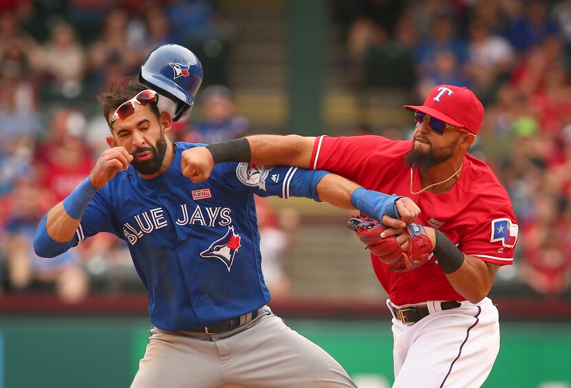 José Bautista (19) recibe un golpe en el rostro de parte de Rougned Odor de los Rangers de...