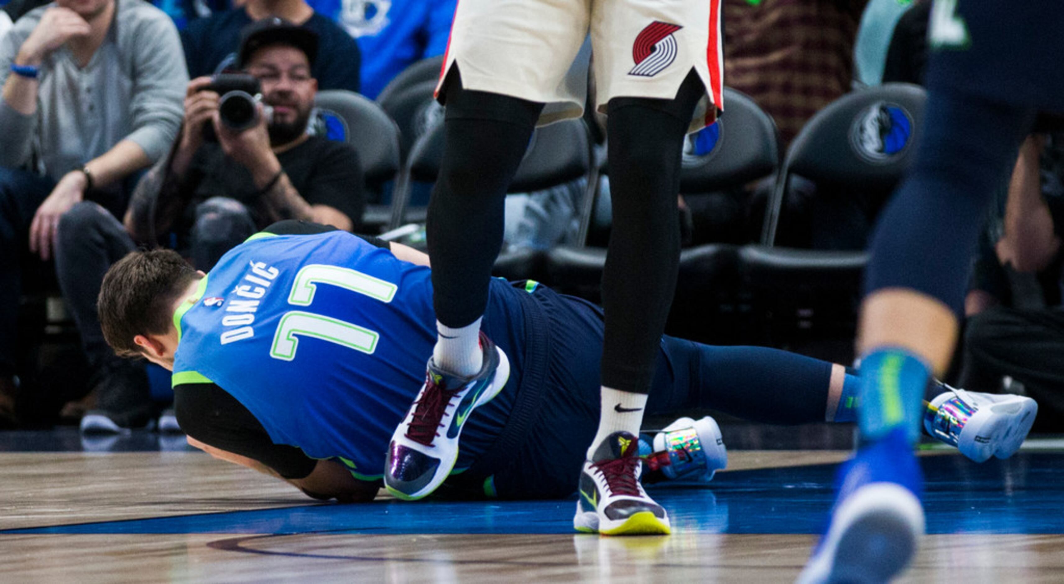 Dallas Mavericks forward Luka Doncic (77) lays on the ground after colliding with Portland...
