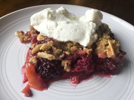 Peach and berry crisp topped with whipped cream.
