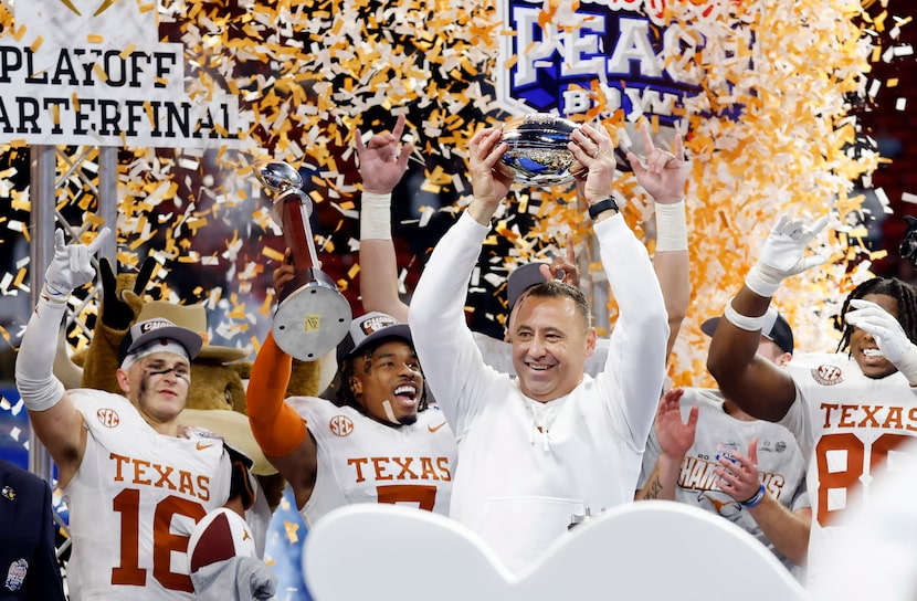 Texas Longhorns coach Steve Sarkisian hoisted the Peach Bowl trophy as defensive back Jahdae...