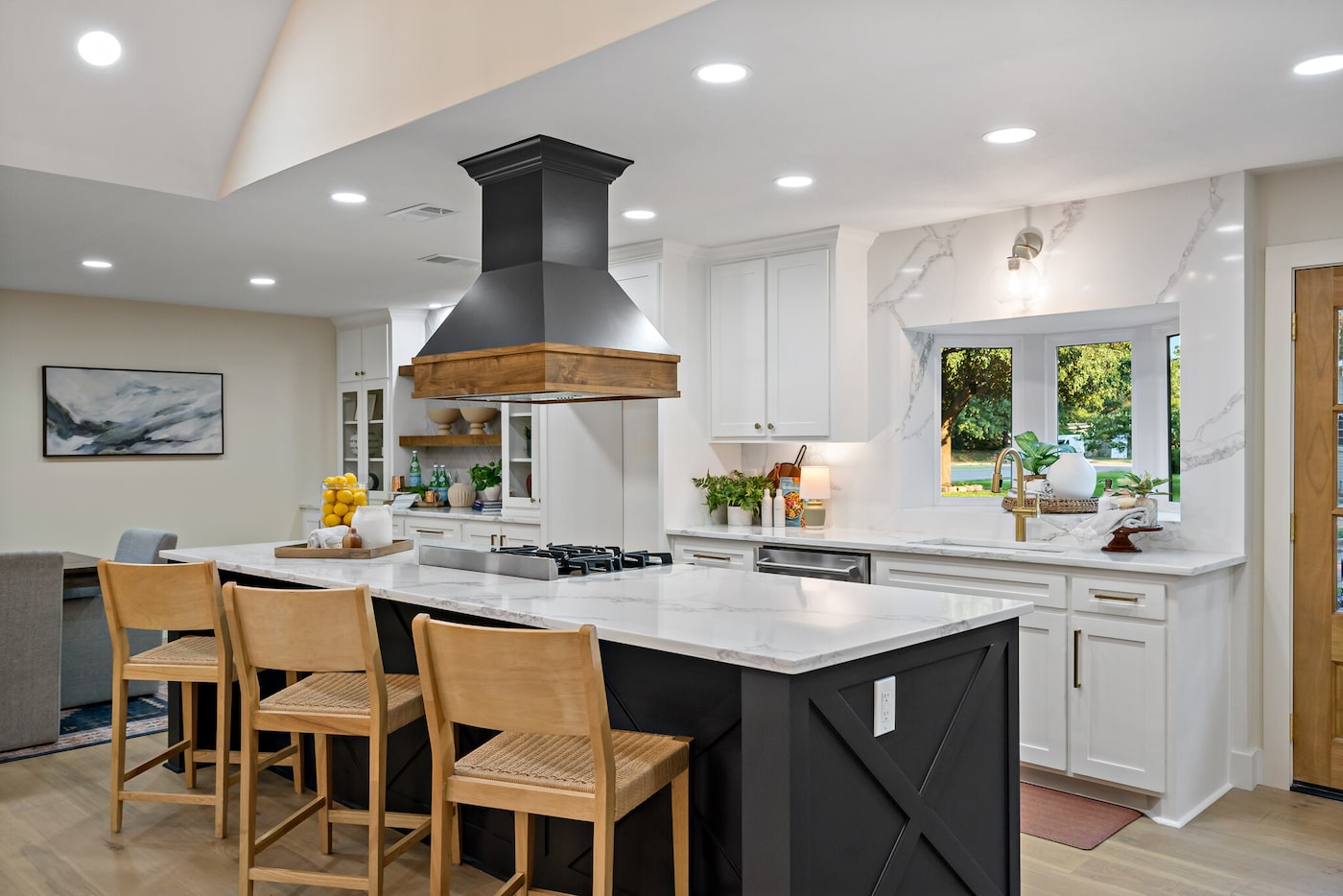 Open-concept kitchen with large island with black, painted base, white cabinetry on far wall...