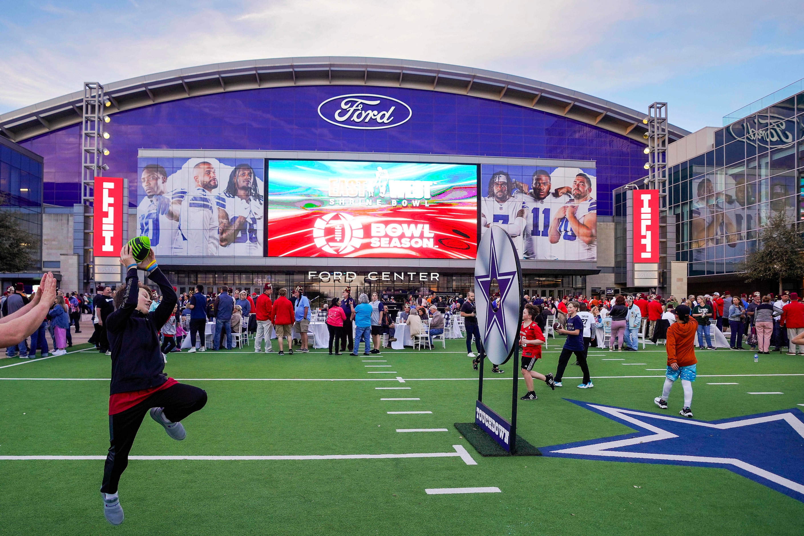 Fans toss a football on the plaza outside before the East-West Shrine Bowl all-star football...