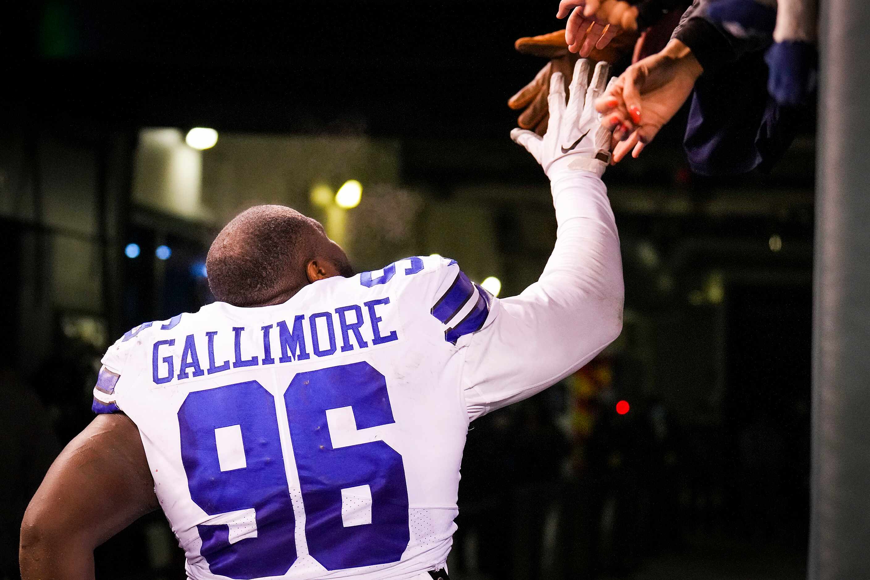 Dallas Cowboys defensive tackle Neville Gallimore high fives fans as he leaves the field...