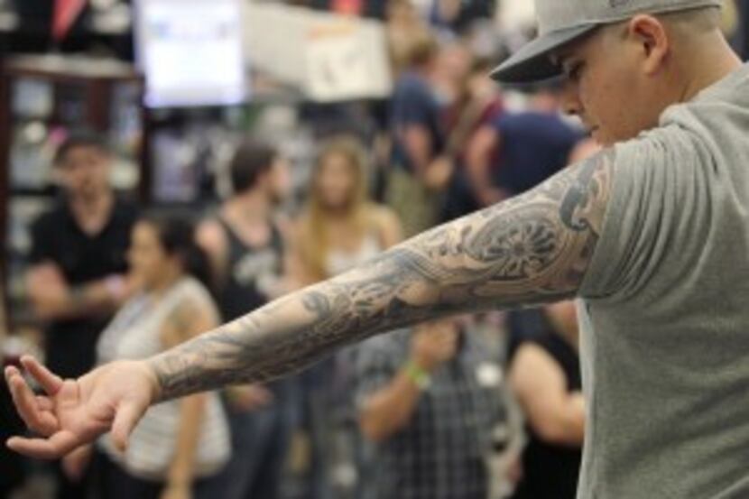  Josh Arenas of Dallas winner of the best sleeve tattoo shows his to the audience during the...