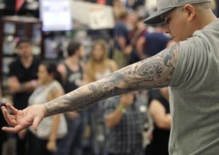  Josh Arenas of Dallas winner of the best sleeve tattoo shows his to the audience during the...