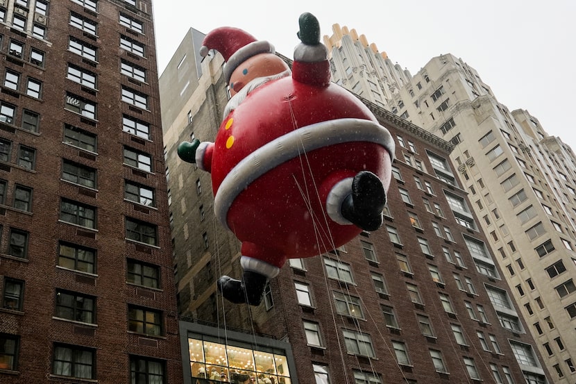 Los manipuladores guían un globo de Santa Claus por la Sexta Avenida durante el Desfile de...