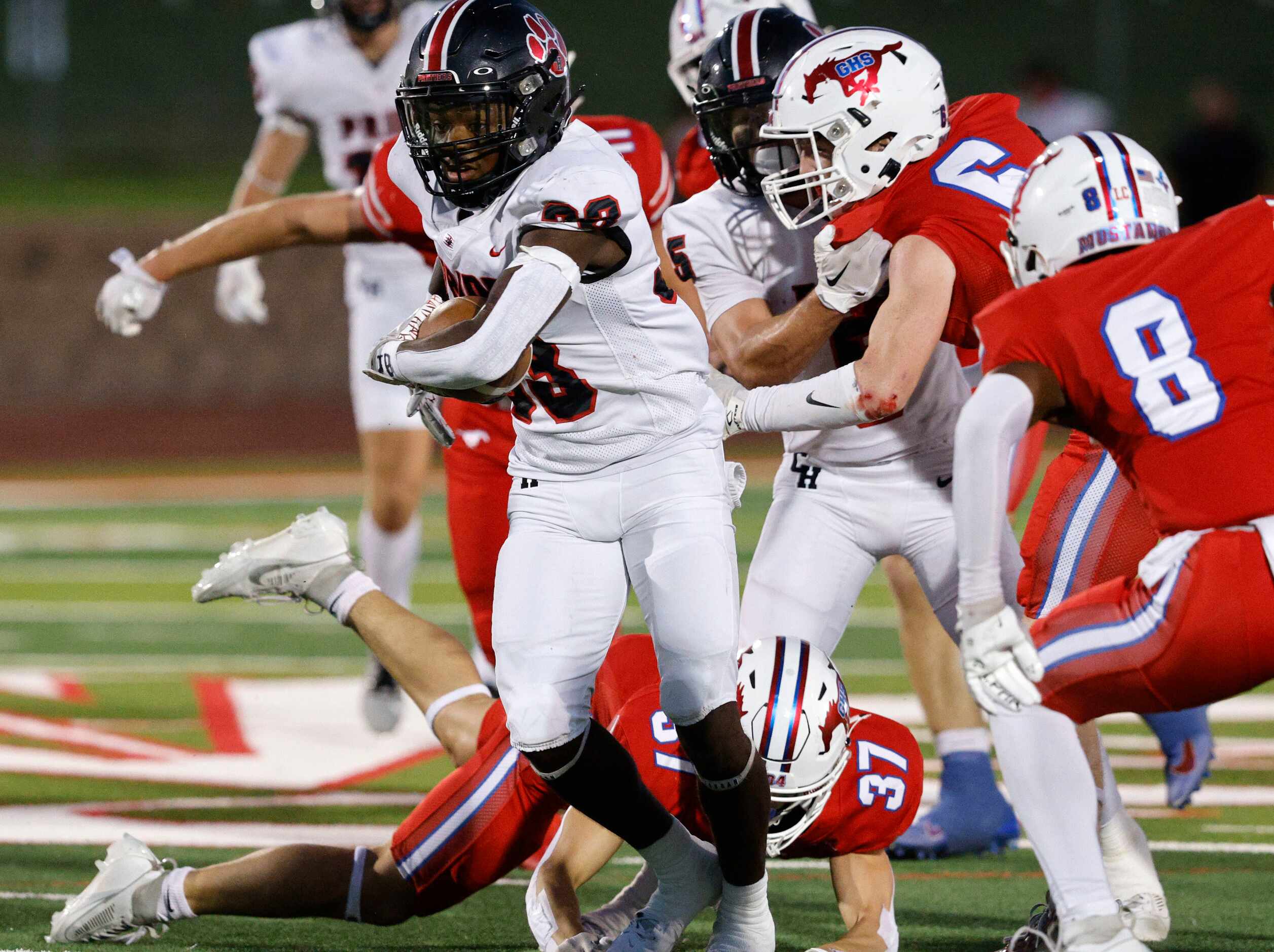 Colleyville Heritage's Colin Bennett (33) carries the ball as Grapevine defense players try...