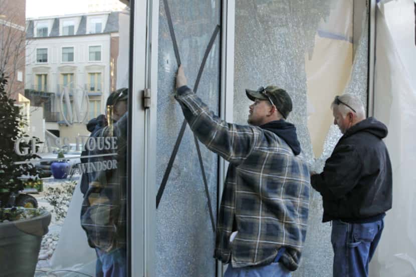 Charles Edwards (left) and Ken Brown of Binswanger Glass tape up the shattered glass at the...