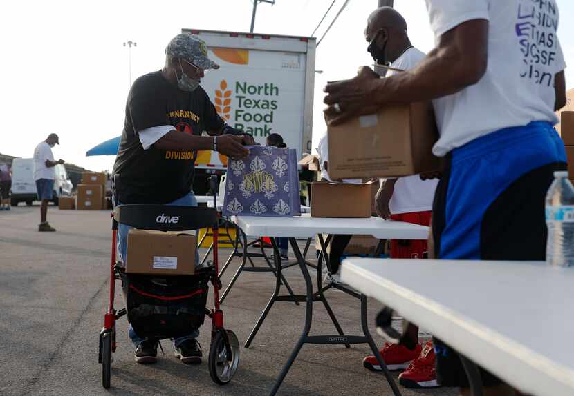 Volunteer Alfred Thomas (right) helps Michael Dotson with food as he makes his way through...
