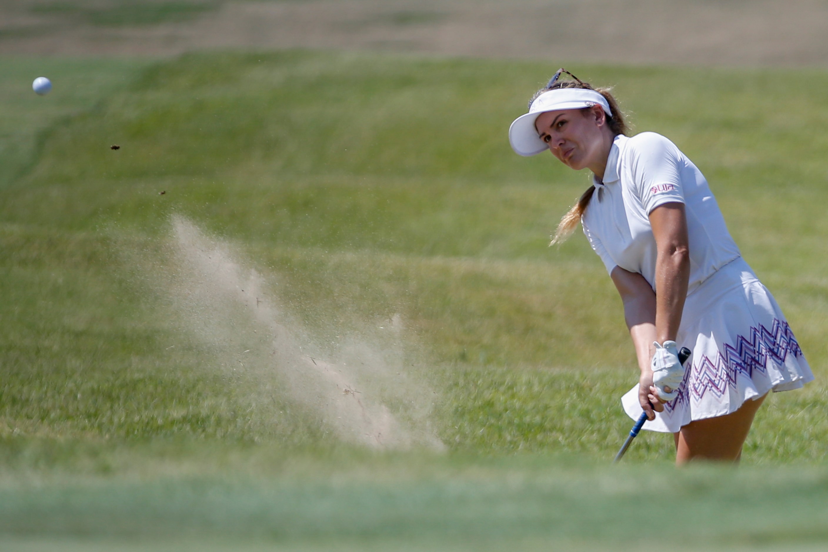 Professional golfer Sydnee Michaels plays a shot out of the 17th green side bunker during...