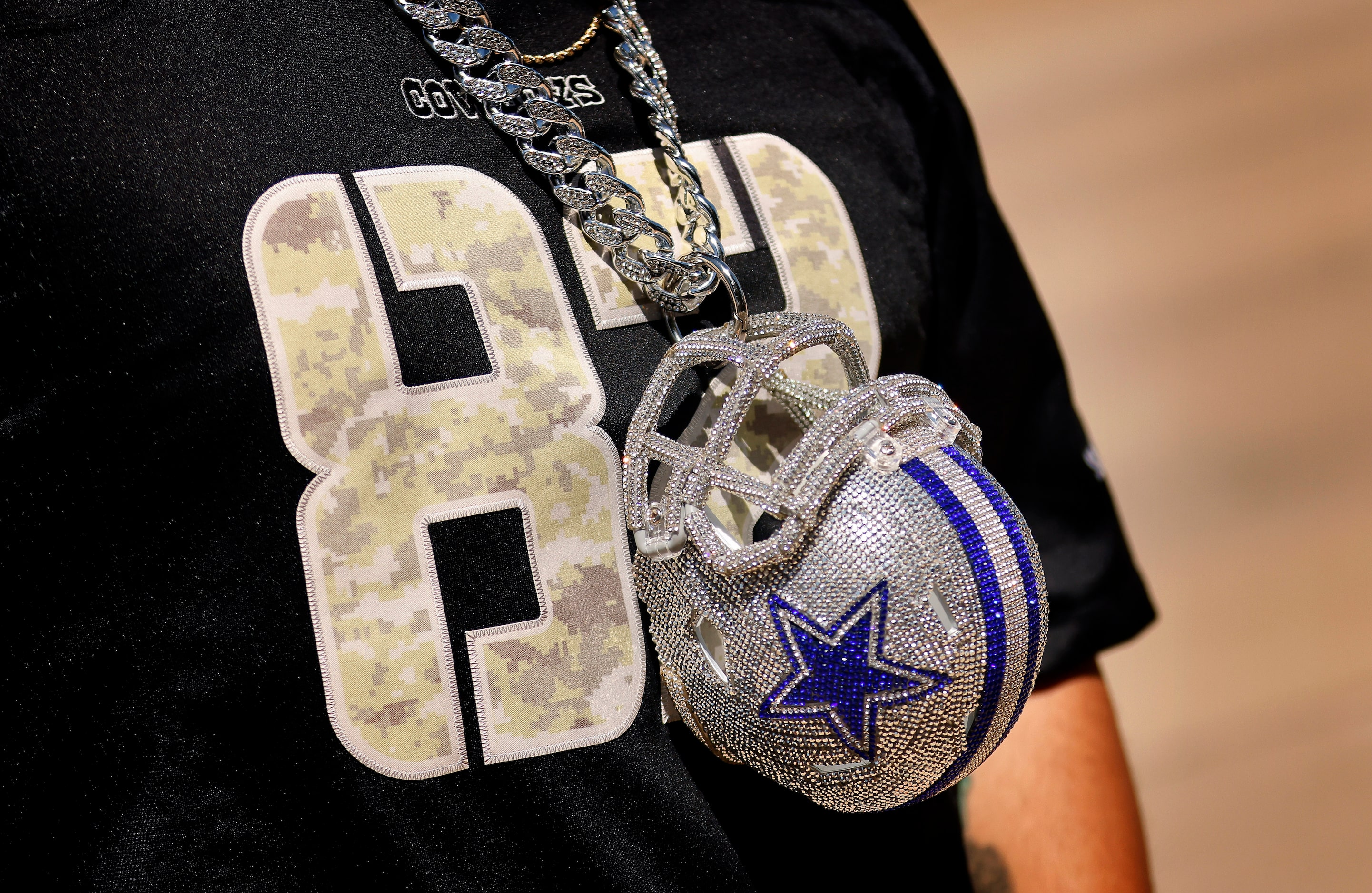 A Dallas Cowboys fan wears a bedazzled helmet around his neck as he arrives for the home...