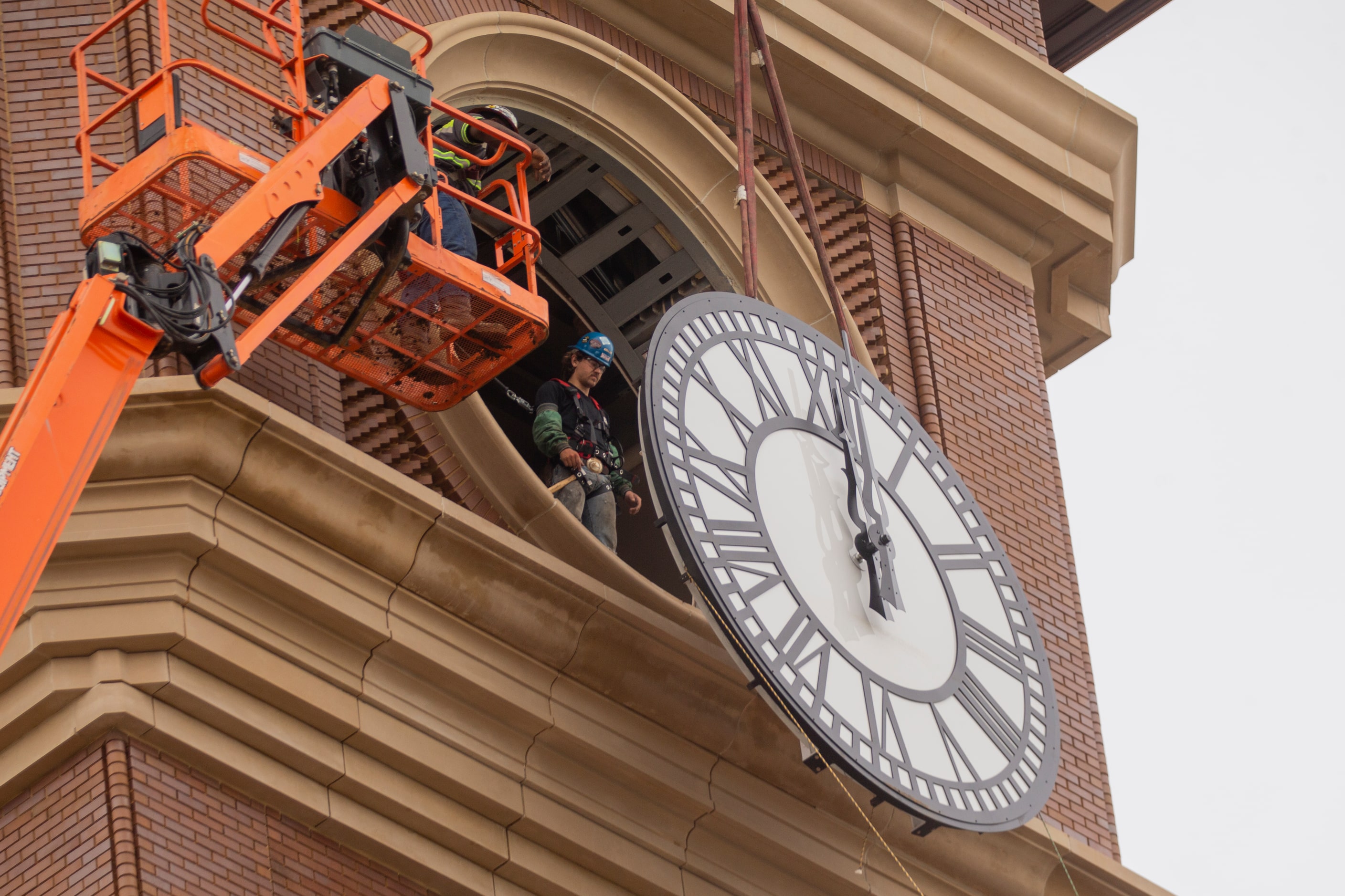 Workers from MEI Rigging & Crating work to install a 12-foot glass clock on the Grapevine...