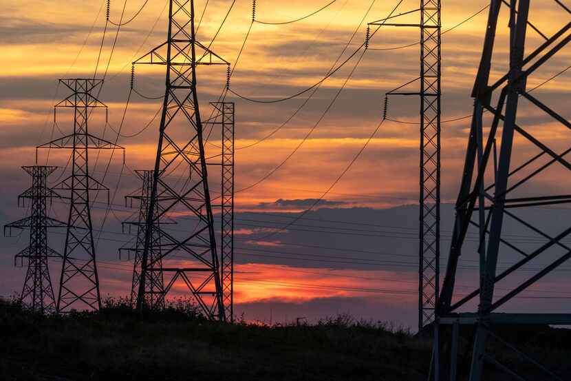 The sun sets behind electricity towers along Mountain Creek Parkway in Dallas on Wednesday,...