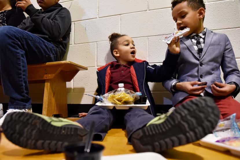 Elon Mitchell, left, tries to feed his brother Maxwell Mitchell a snack as the family taste...