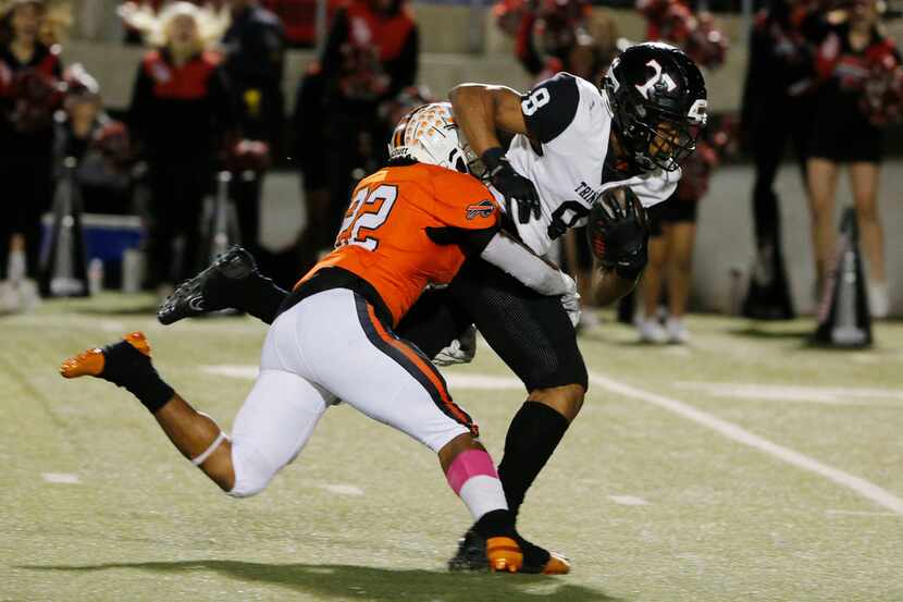Euless Trinity receiver Camryn Hardy (8) makes a catch and is tackled by Haltom's Johnny...