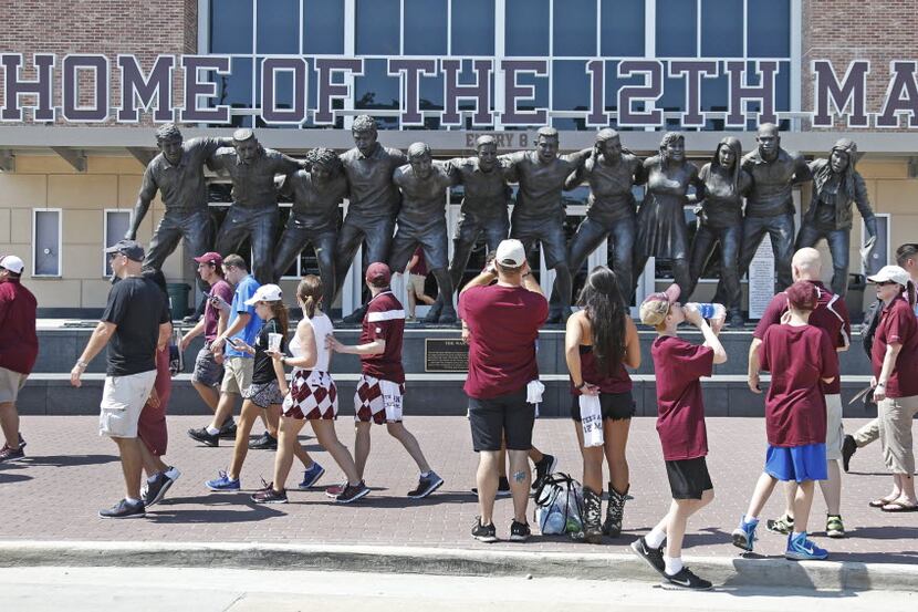 Texas A&M fans take photos by the "12th Man" sculpture outside the stadium before the UCLA...