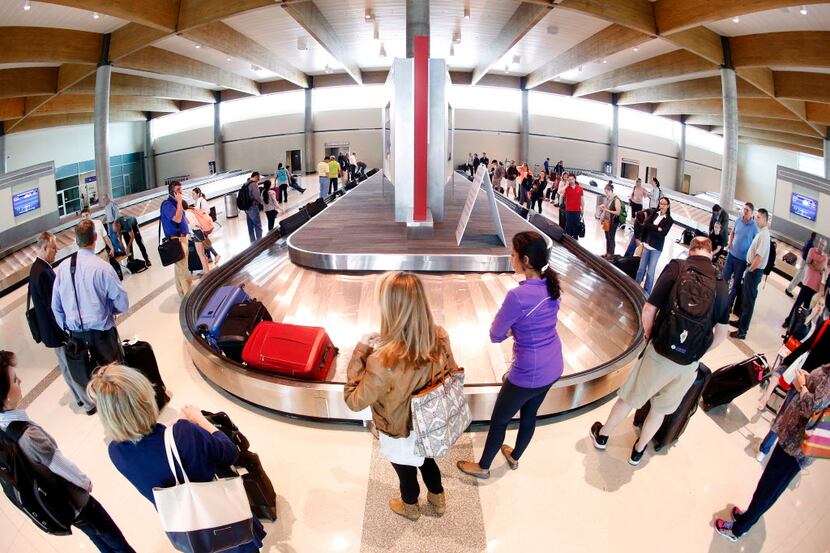  Airline passengers wait for their luggage in the Dallas Love Field baggage claim area in...