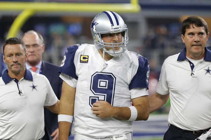 Dallas Cowboys quarterback Tony Romo (9) is assisted off the field by team staff after Romo...