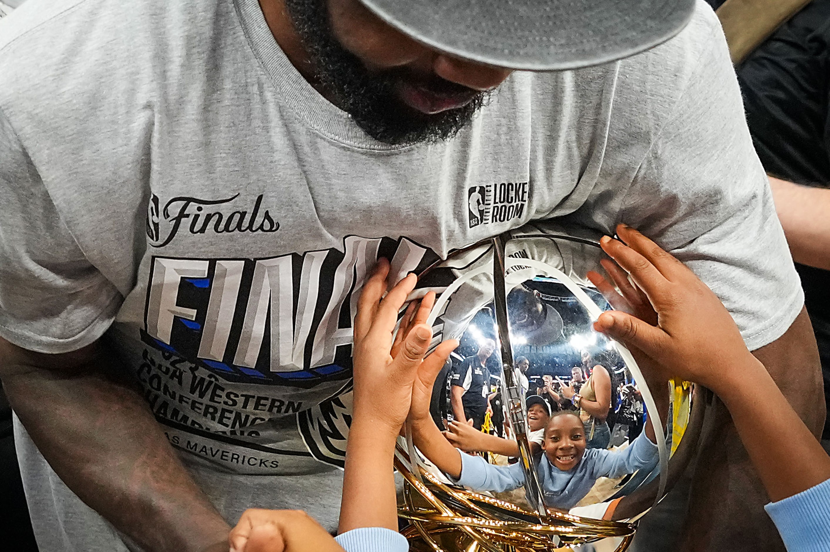 Dallas Mavericks guard Kyrie Irving shows the championship trophy to his family after a...