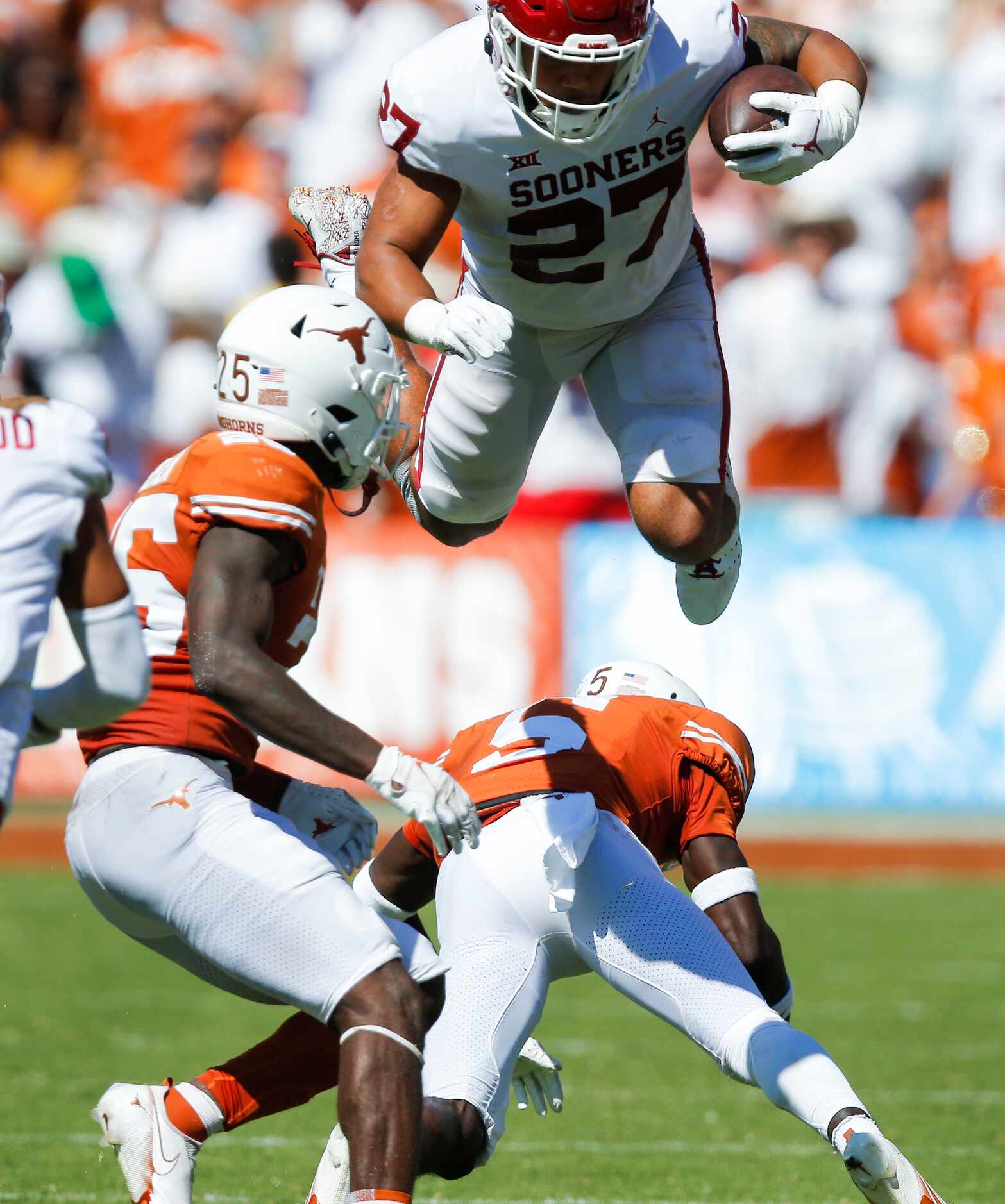 Oklahoma tight end Jeremiah Hall (27) leaps over Texas defensive back D'Shawn Jamison (5)...