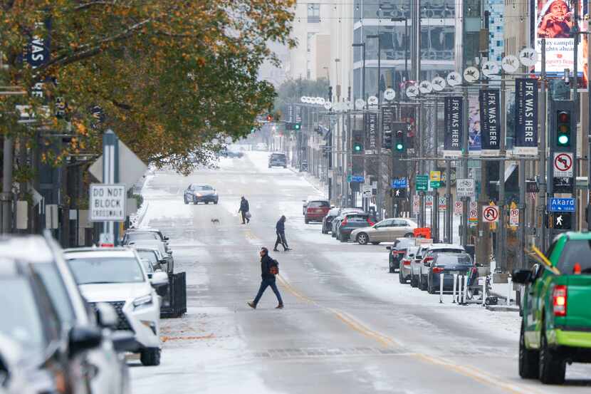People cross snow covered Main St. on Monday, Jan. 15, 2024 in Dallas. 