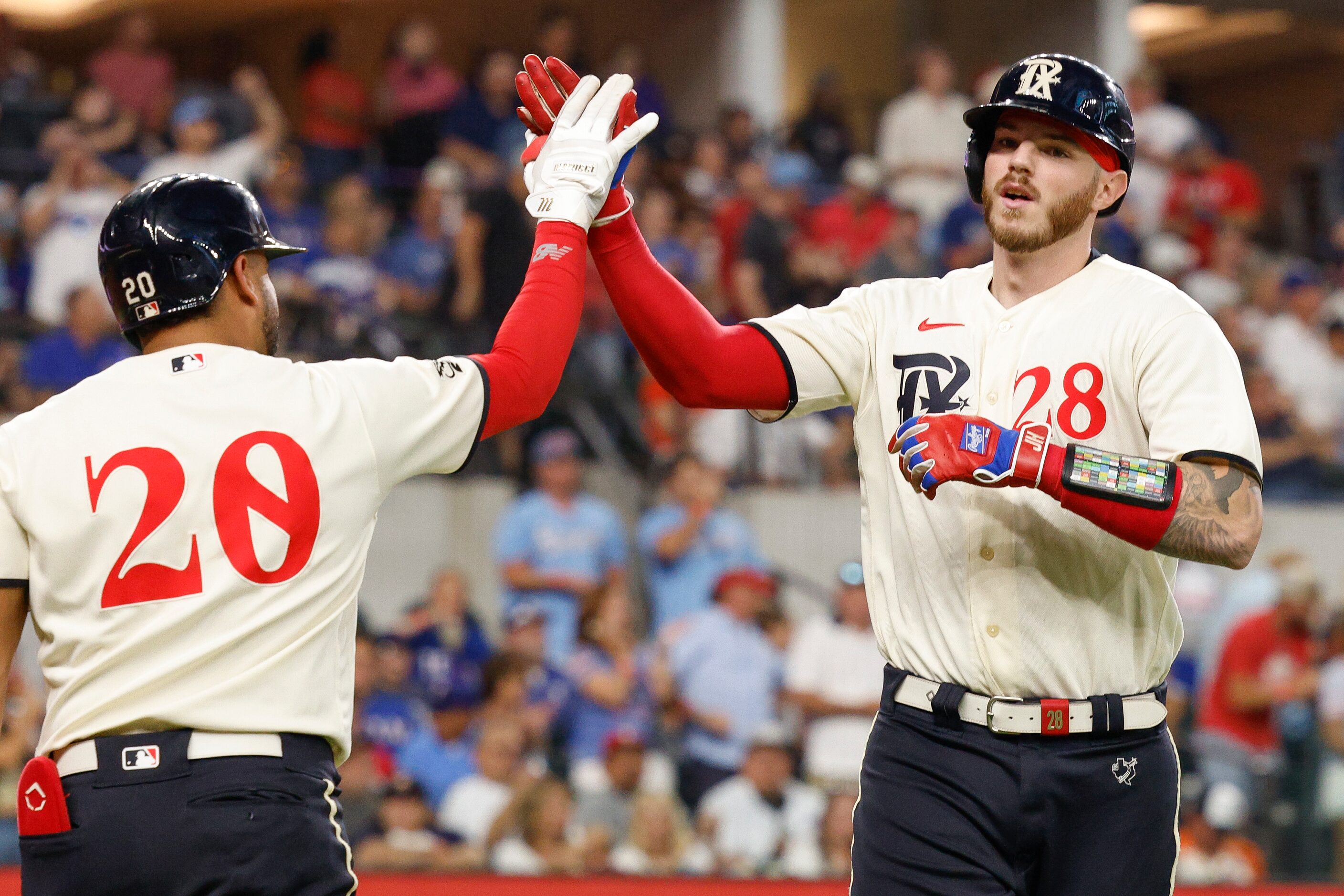 Texas Rangers catcher Jonah Heim (28) high-fives designated hitter Ezequiel Duran (20) after...