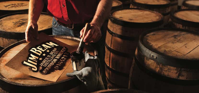 A Jim Beam worker paints the tops of barrels. The company offers tours to the public at Jim...