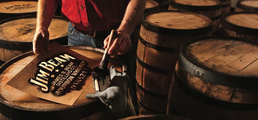 A Jim Beam worker paints the tops of barrels. The company offers tours to the public at Jim...