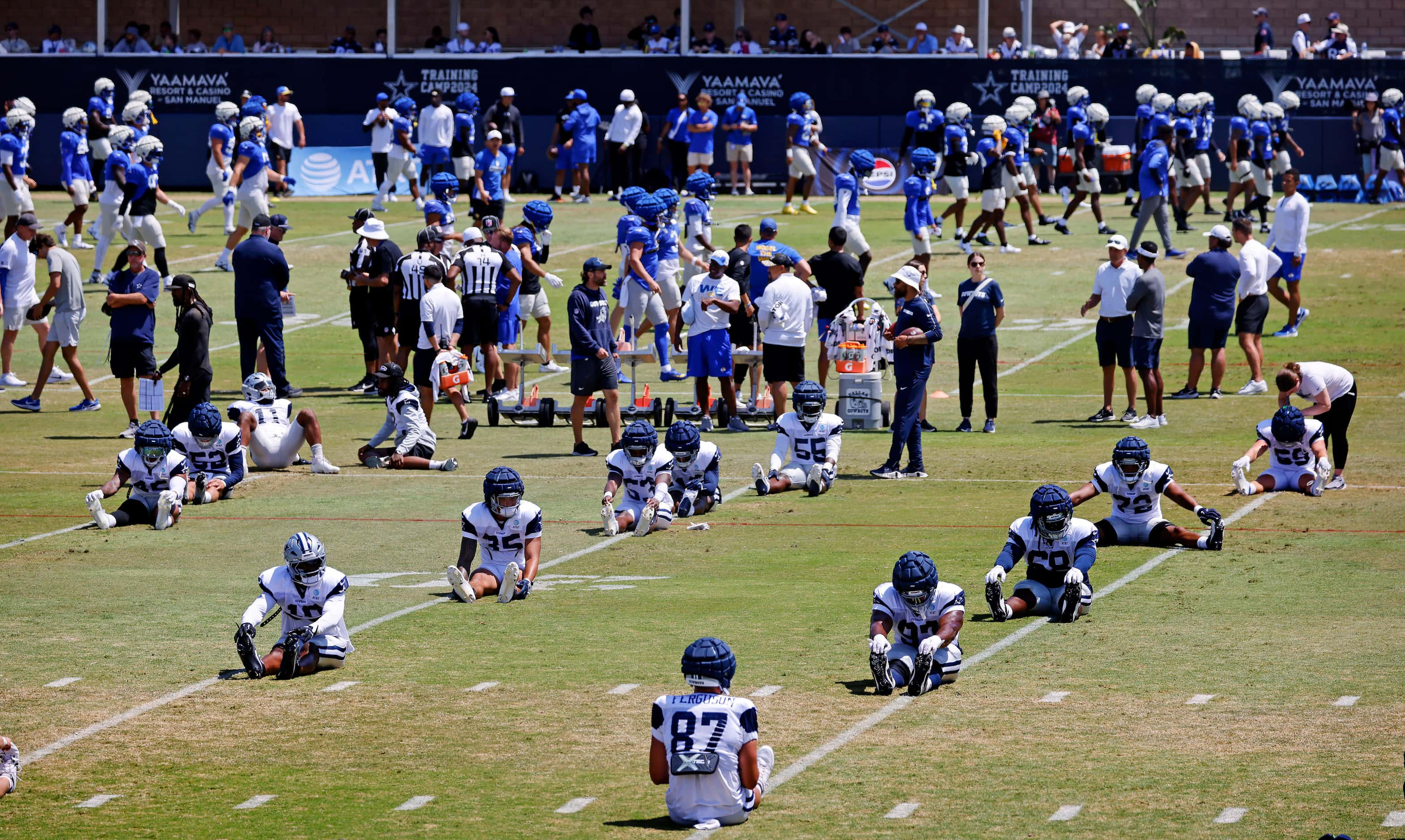 The Dallas Cowboys (foreground) and Los Angeles Rams (background) stretch and warmup before...