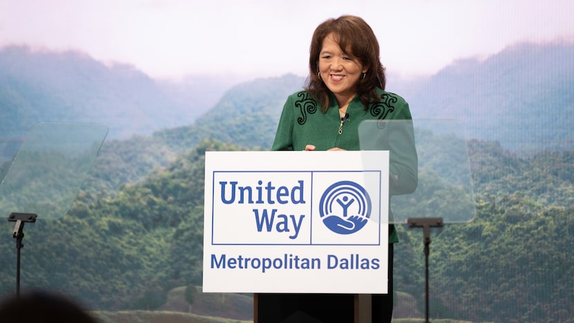 Anne Chow wears a green jacket and stands behind a podium, with a sign for United Way of...