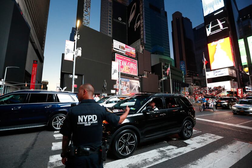 A police officer directs traffic in Times Square during a widespread power outage, Saturday,...