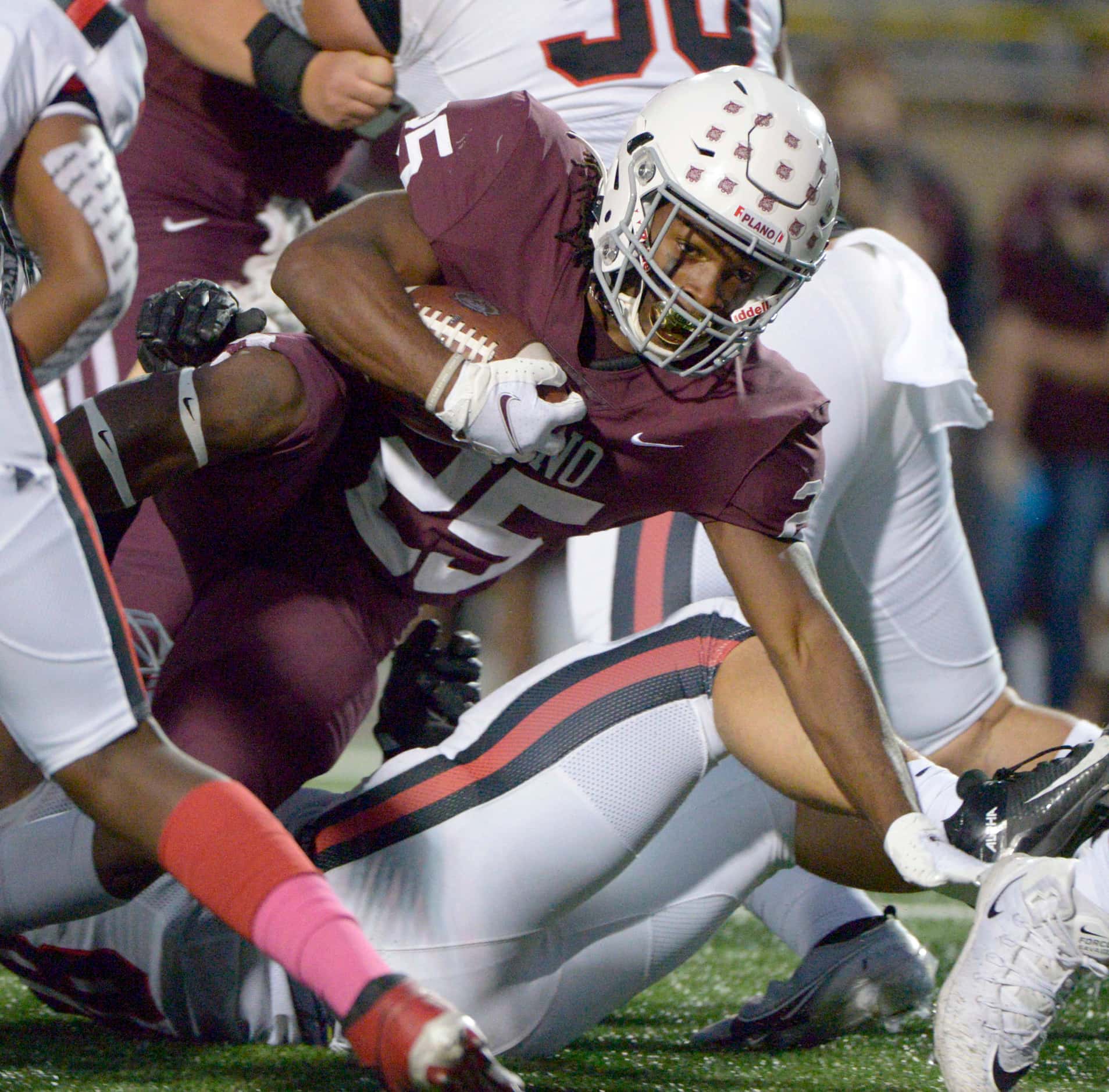 Plano’s Tylan Hines tries to stay on his feet as he runs through the Lake Highland defense...
