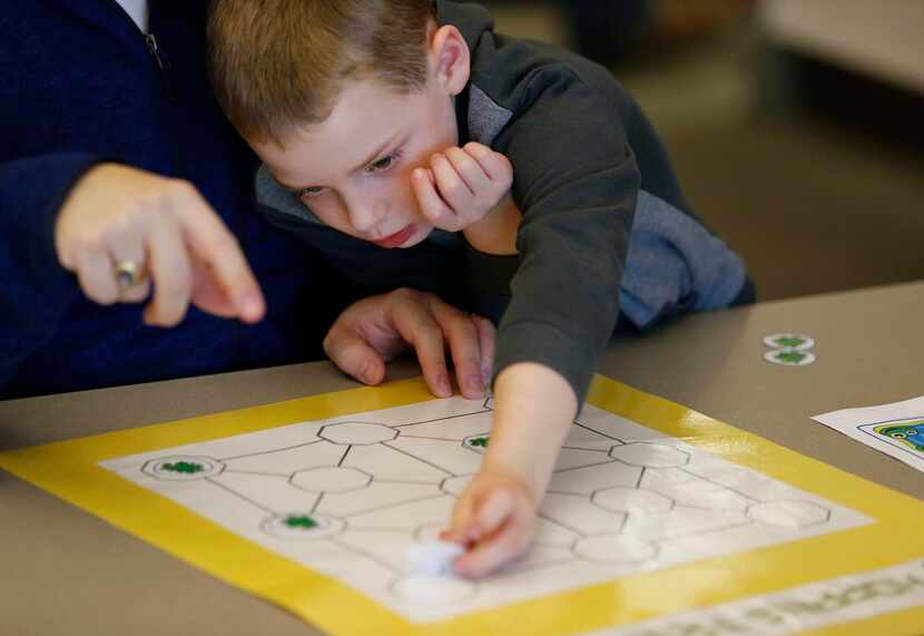 
Callum Tiller, 6, works with his father, Chris Tiller of Plano, on solving a puzzle during...
