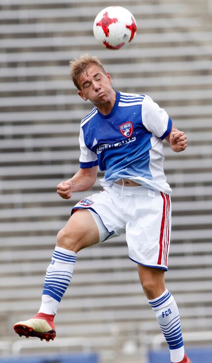 FC Dallas' Paxton Pomykal (19) heads the ball away from an Arsenal FC opponent during first...