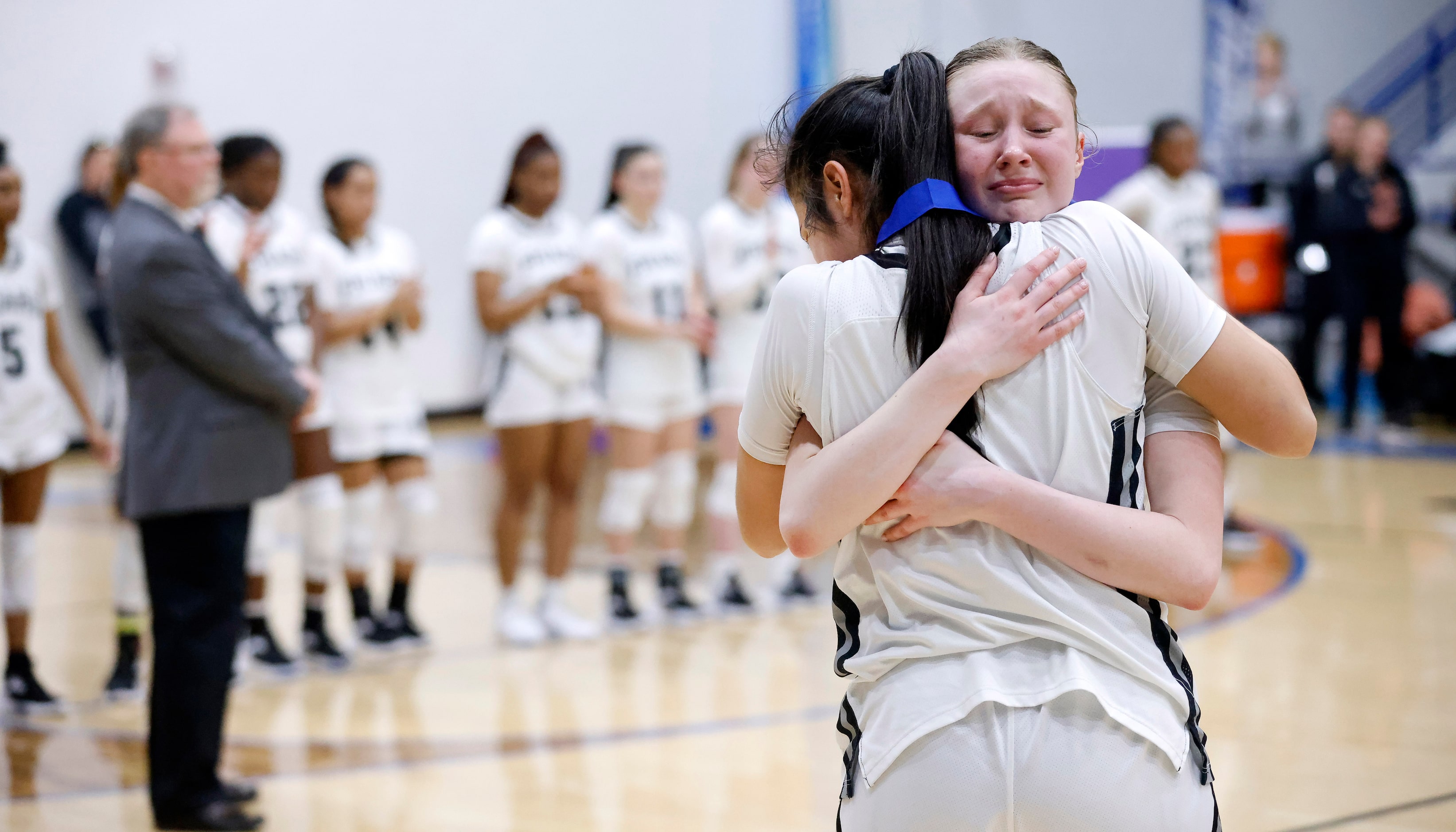 Bishop Lynch players Maddie Heiss (2, facing) and Natalie Cardenas (3) hug following their...