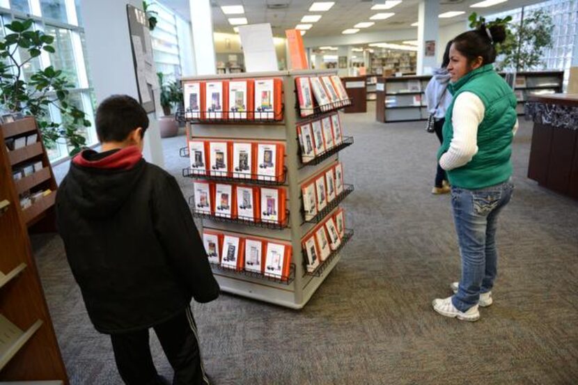 
Balda Aguilar and her son Jesus Aguilar, 9, look at a rack of stories on individual mp3...