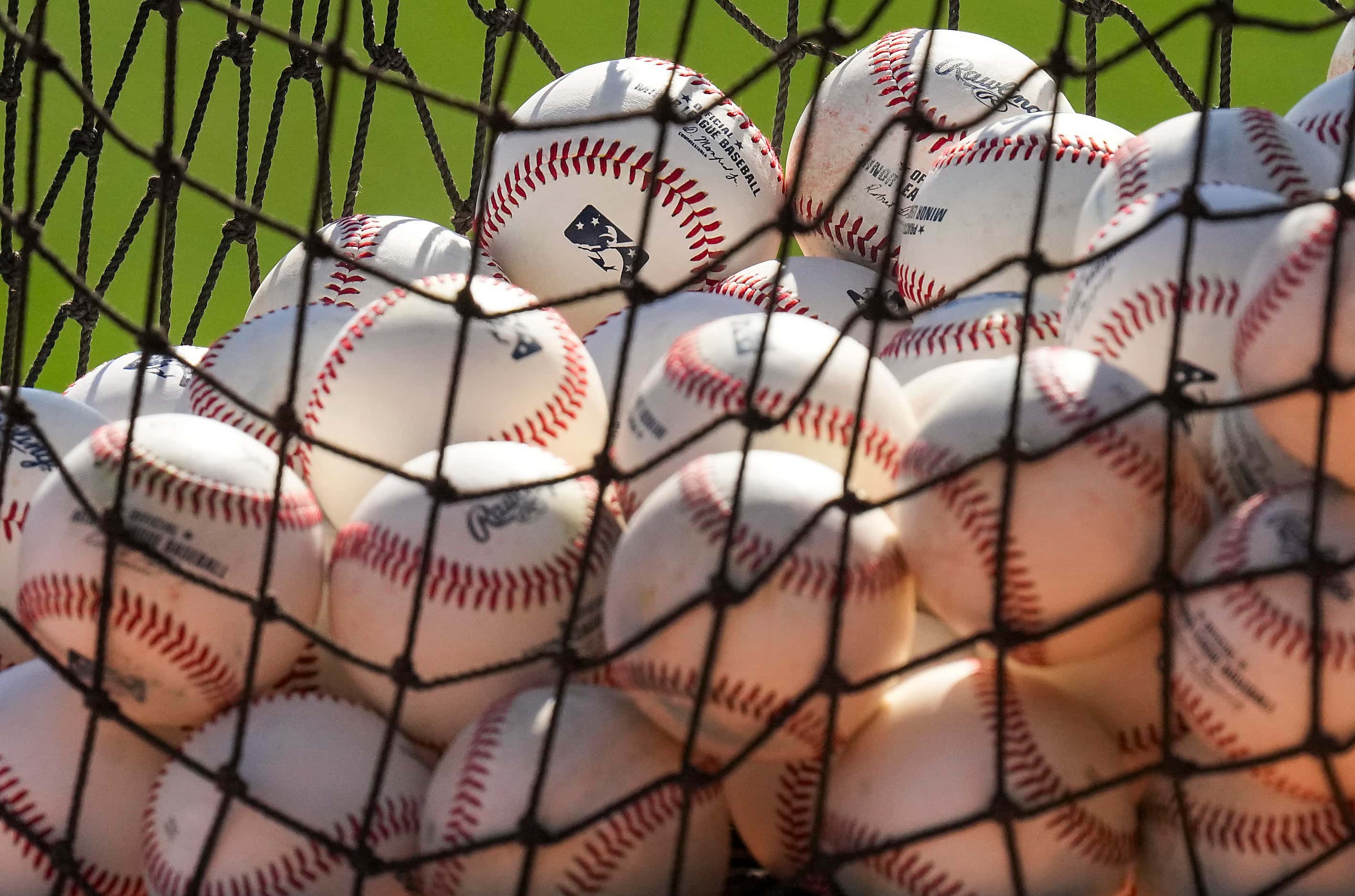 A basket of practice baseballs sits ready for a fielding drill during a Texas Rangers spring...