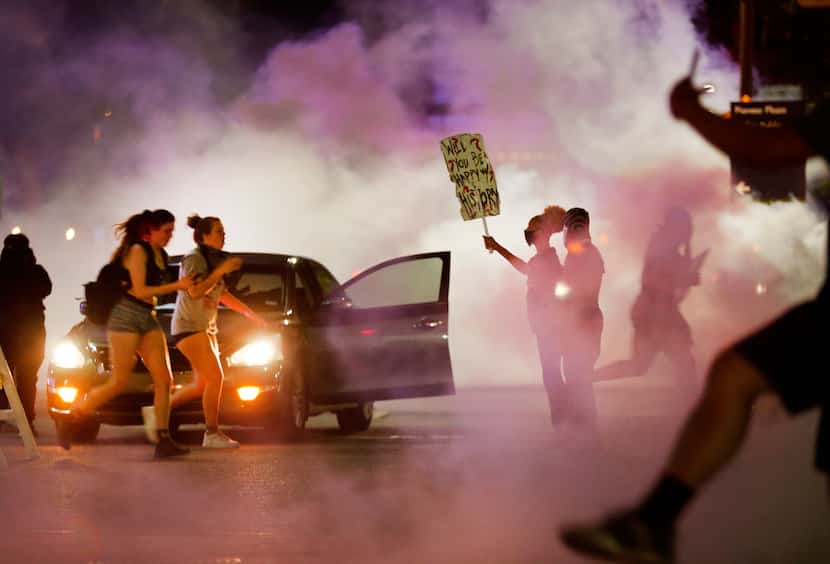 Protesters are overcome by tear gas as they run police officers during demonstrations in...