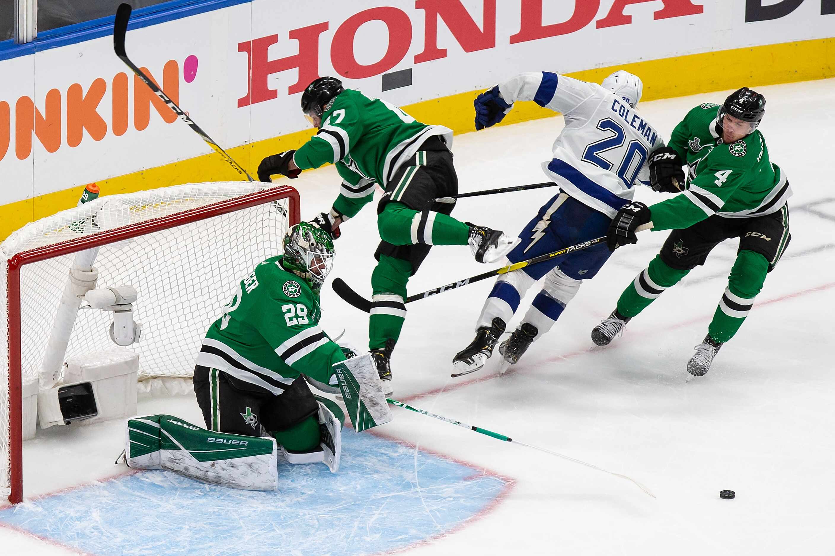 Goaltender Jake Oettinger (29) of the Dallas Stars pokes the puck away from Blake Coleman...