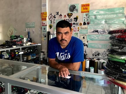 Lazaro Garcia, who works at a window-tinting shop near the banks of the Rio Grande, applauds...