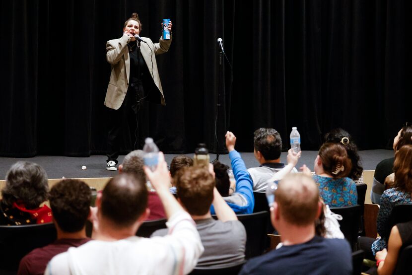 Devon Kodzis of The Story Collider cheers toward the crowd while taking medication during an...