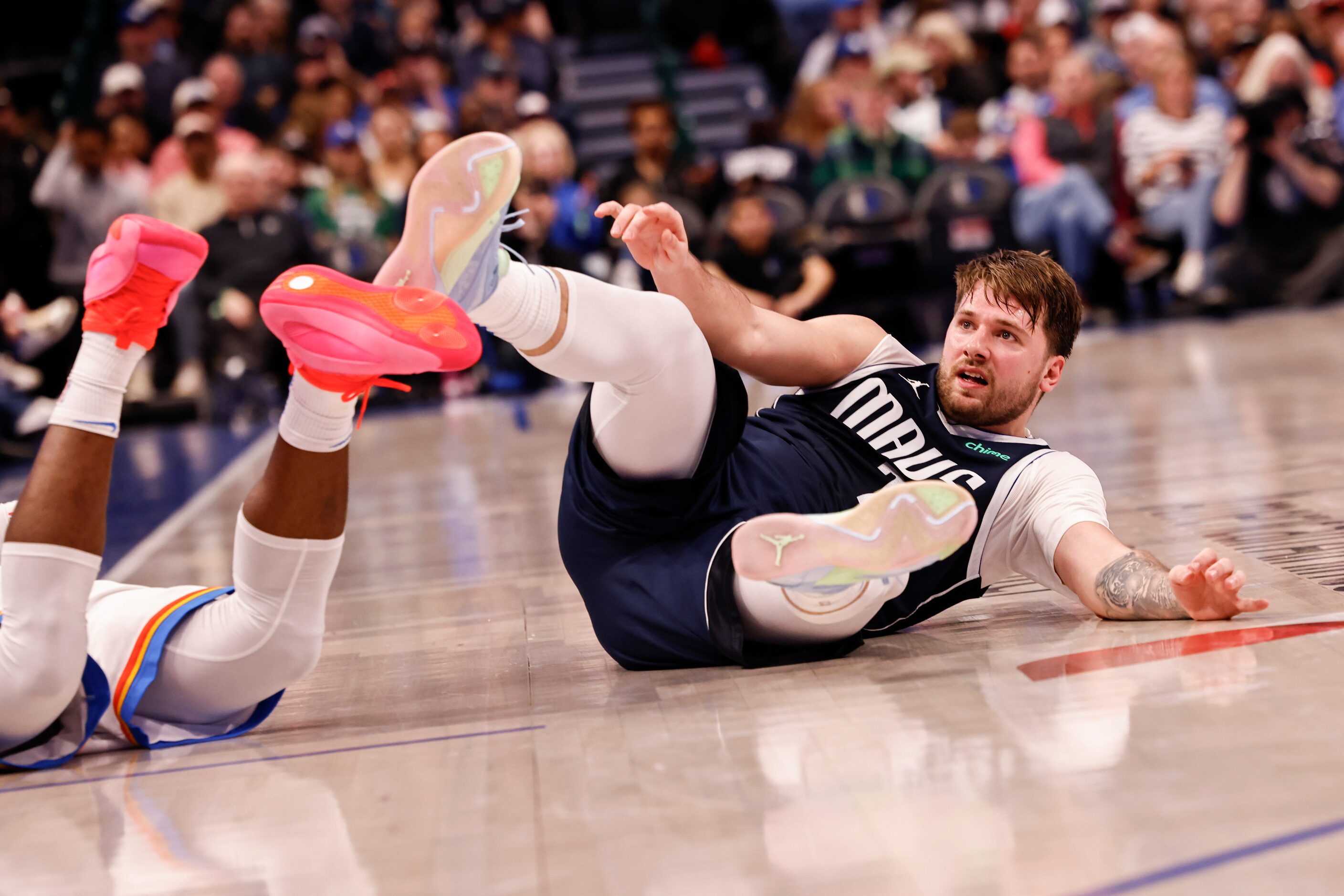 Dallas Mavericks guard Luka Dončić (77) falls to the ground after colliding with Oklahoma...