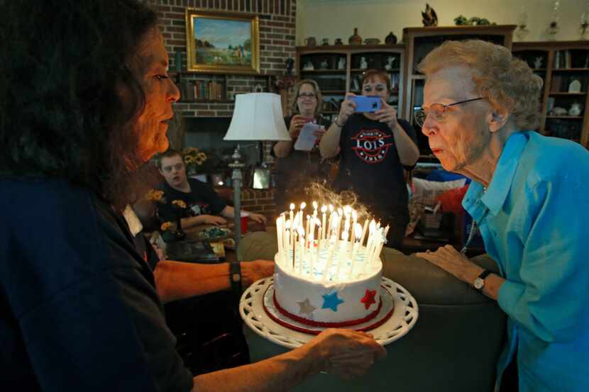 Lois Kreger blew out the candles on her cake, held by Sunny Yeatts, during Kreger's 100-year...