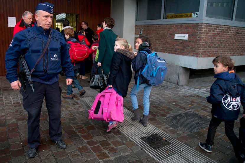 Children passed a police officer  in Brussels as they arrived for school Wednesday after a...