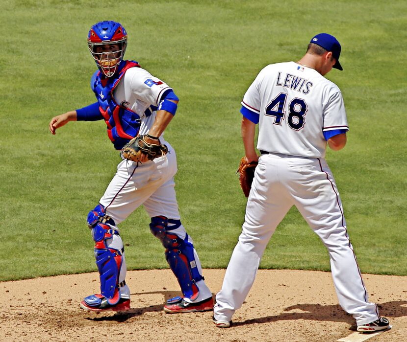 Texas Rangers catcher Robinson Chirinos (left) heads back to the plate after trying to talk...